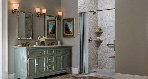 A large bathroom with a walk-in shower, green double vanity and two square mirrors. 